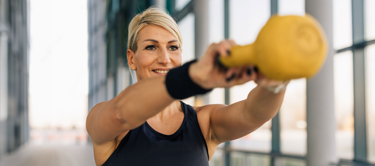 Mujer realizando un entrenamiento con peso en el gimnasio.