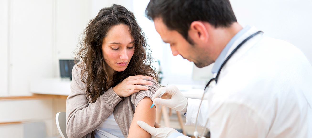 Médico aplica vacuna con jeringa en el brazo de una mujer para un viaje seguro.