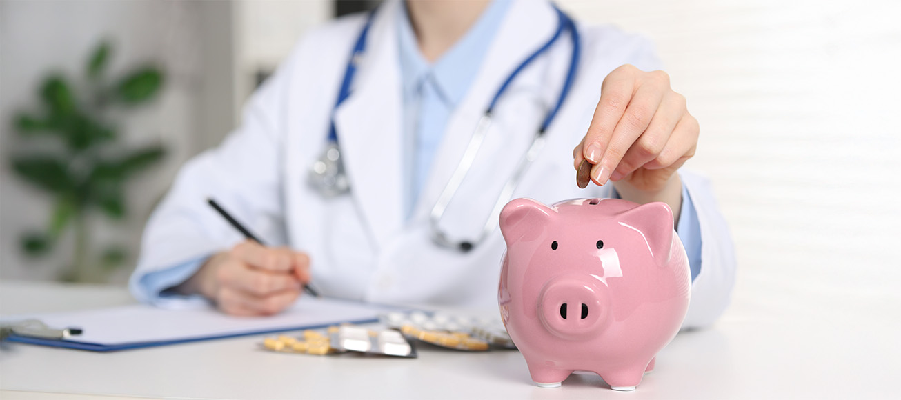 Profesional sanitario con bata y fonendoscopio introduce moneda en hucha de cerdito, simbolizando ahorro financiero.