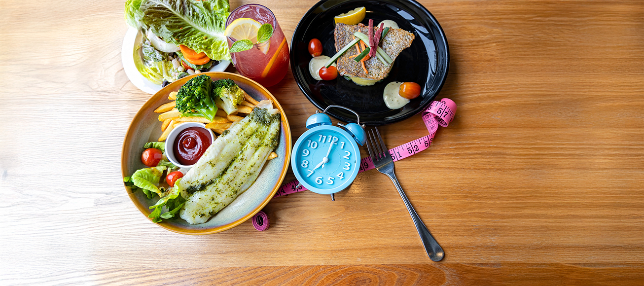 platos de comida con un reloj que simboliza los momentos diarios para comer.