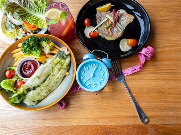 platos de comida con un reloj que simboliza los momentos diarios para comer.