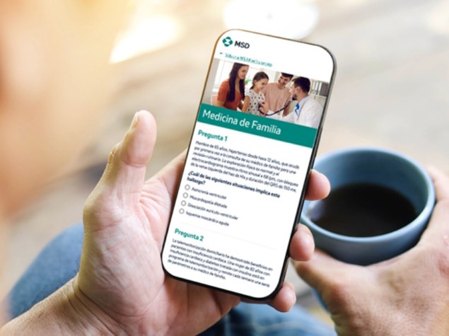 Manos sostienen móvil con cuestionario de Medicina de Familia del MIR 2025 y café.
