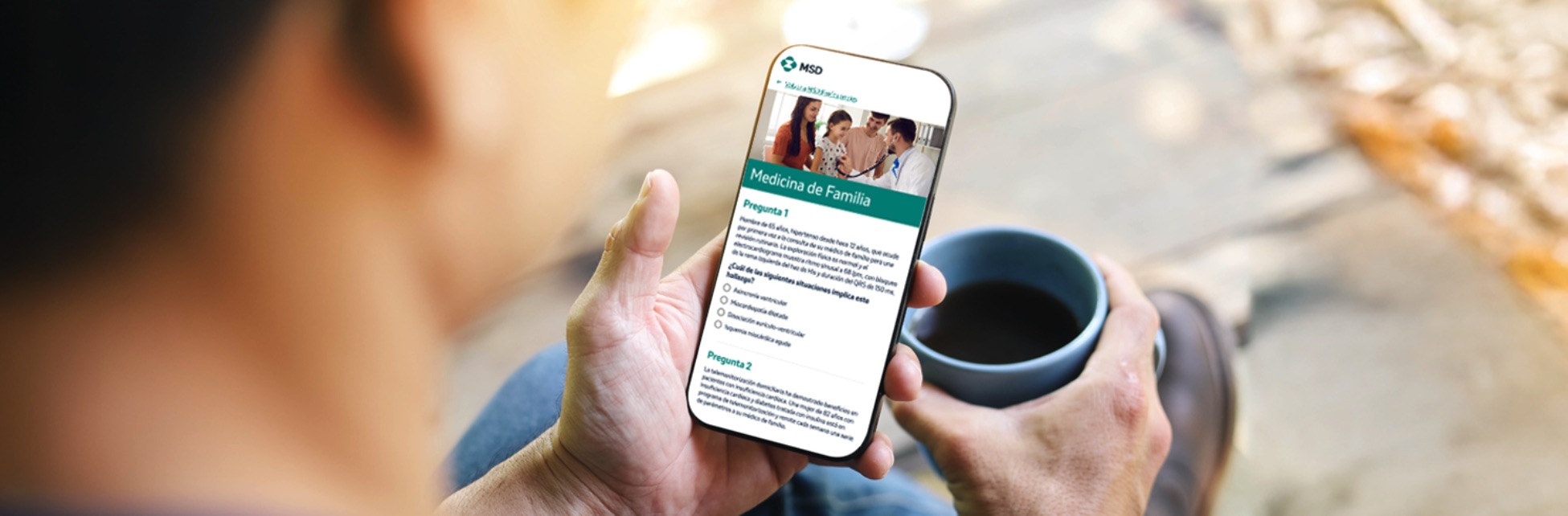 Manos sostienen móvil con cuestionario de Medicina de Familia del MIR 2025 y café.