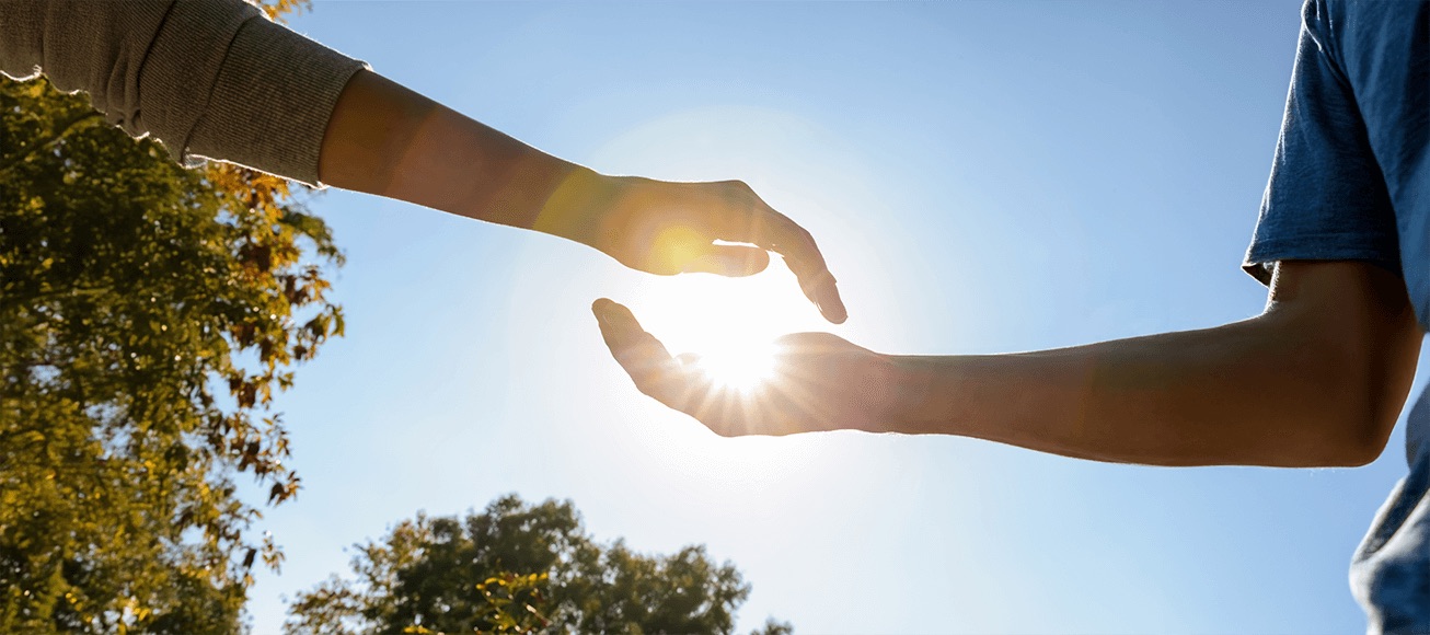Dos manos al aire libre enmarcan el sol, simbolizando equilibrio en la exposición solar.