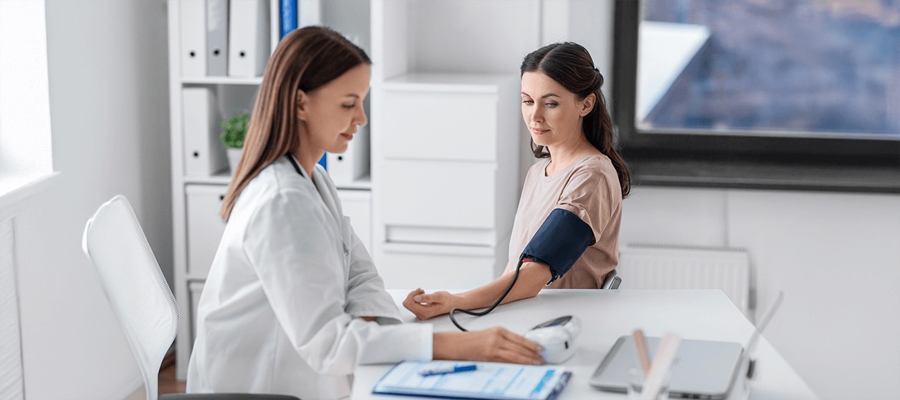 Profesional de salud mide la presión arterial a una mujer con tensiómetro digital