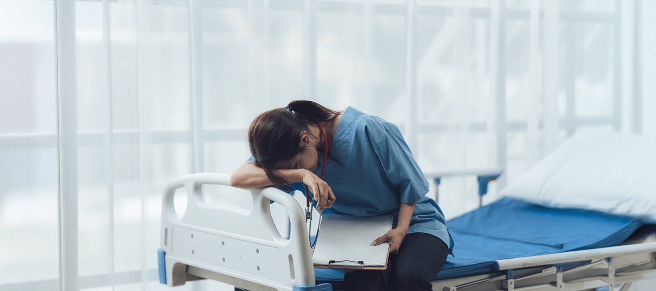 Profesional de la salud con fatiga descansa sobre cama hospitalaria con portapapeles tras turno nocturno.
