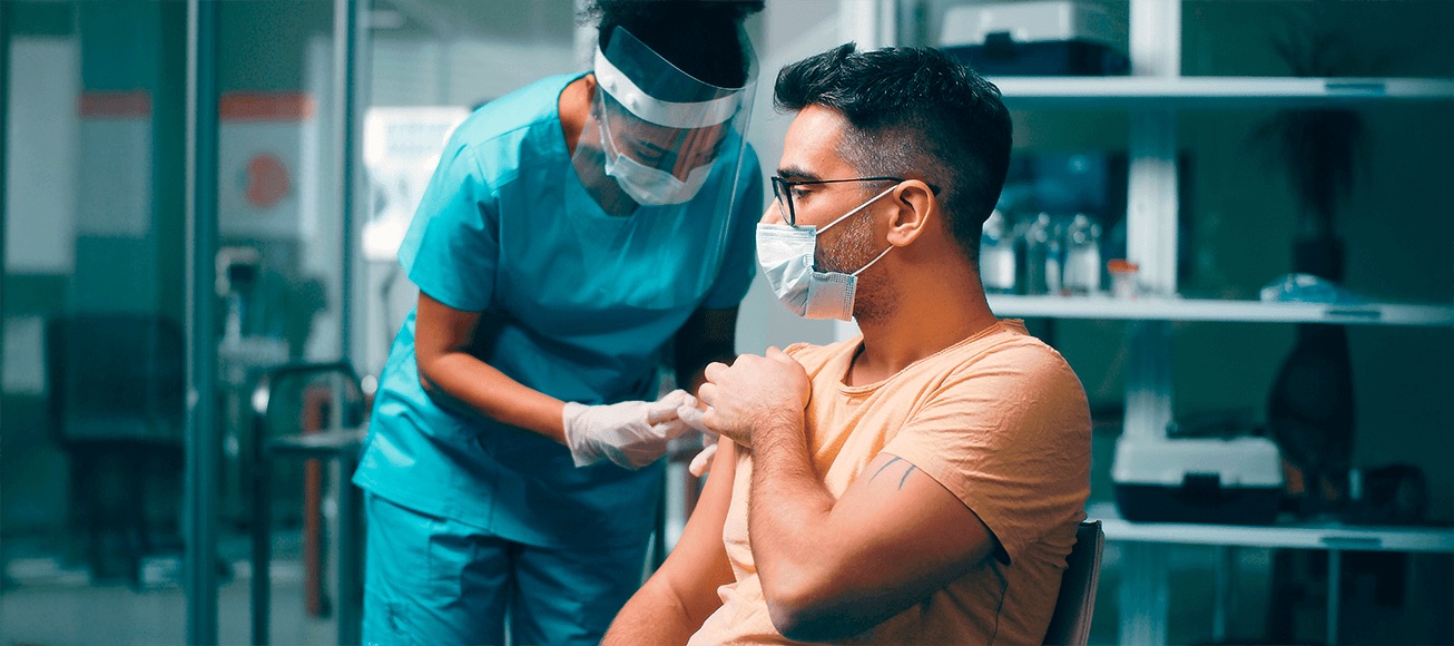 Profesional sanitario con mascarilla y careta vacuna a adulto en consulta clinica, prevencion de futuras pandemias.