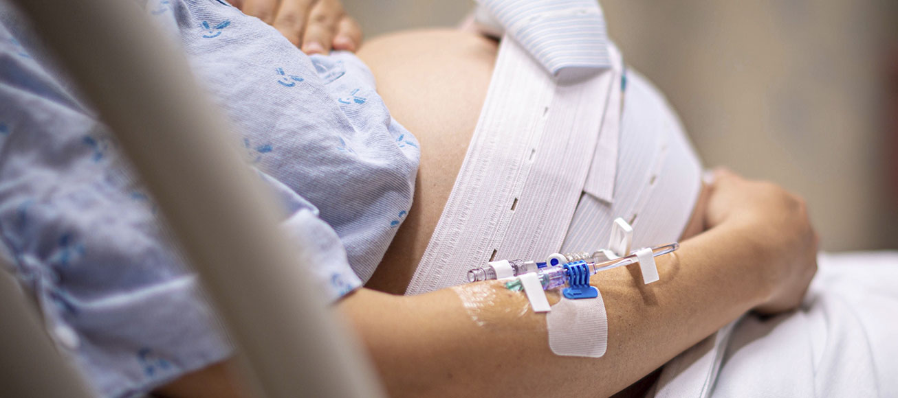 Mujer embarazada con una vía en uno de sus brazos.