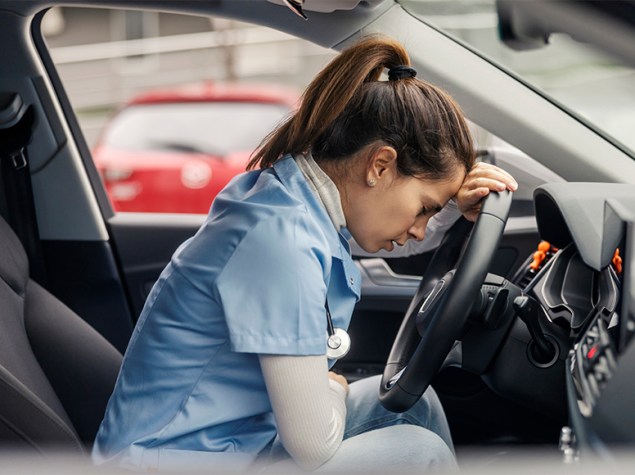 Sanitaria con gesto agotado en su coche antes de conducir.