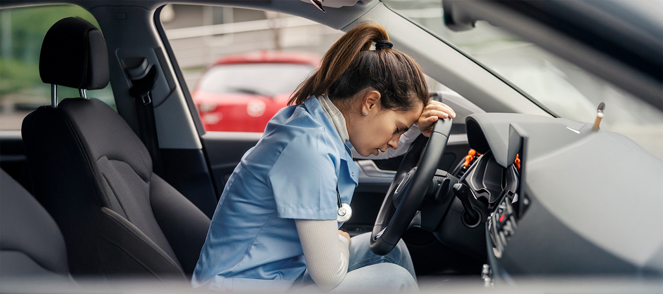 Sanitaria con gesto agotado en su coche antes de conducir.