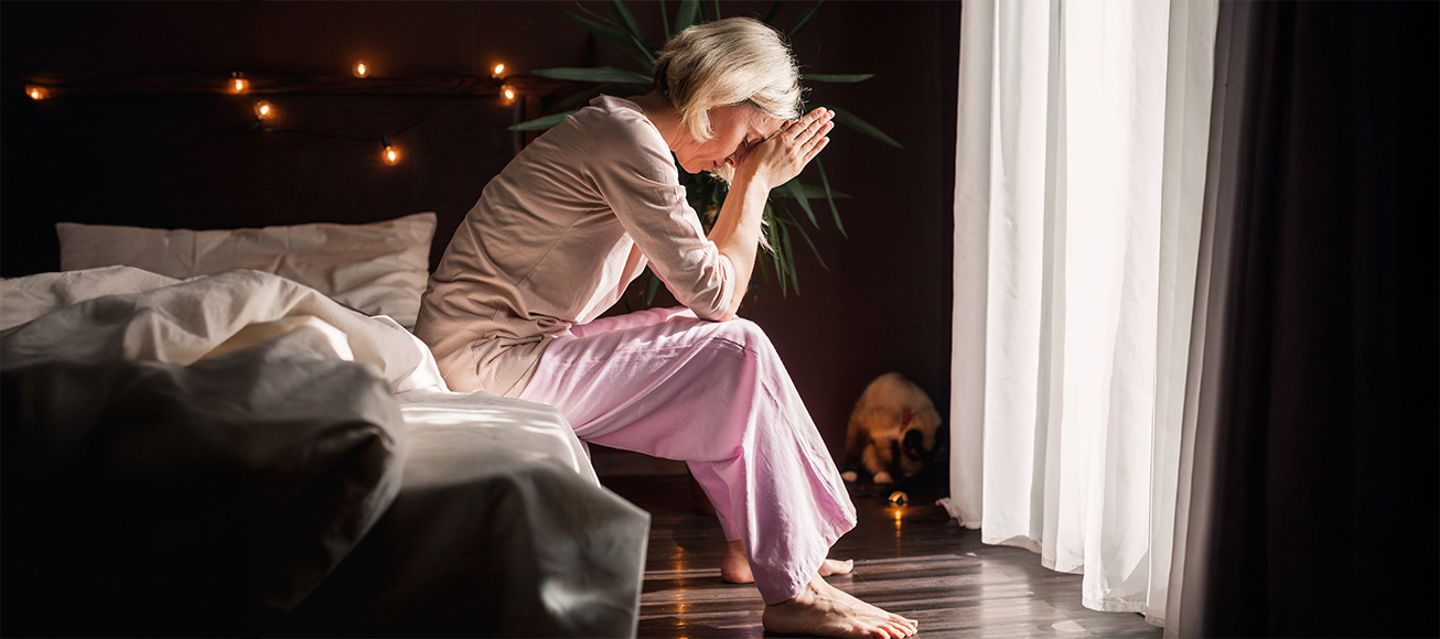 Mujer con insomnio sentada en el borde de su cama.