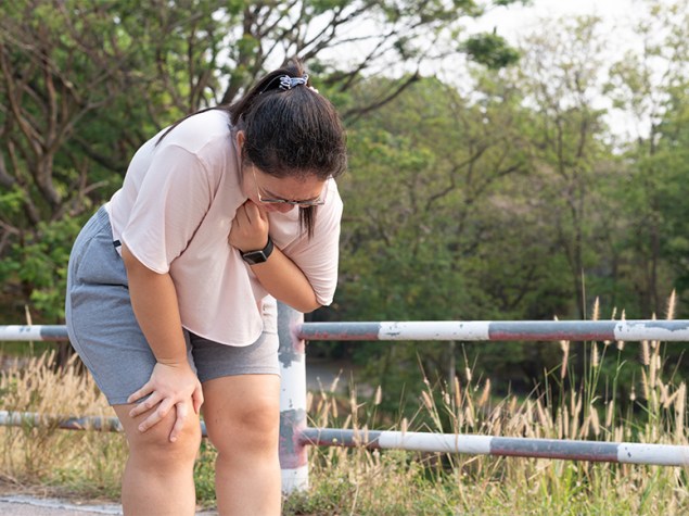Joven con obesidad llevándose la mano al pecho mientras hace deporte.