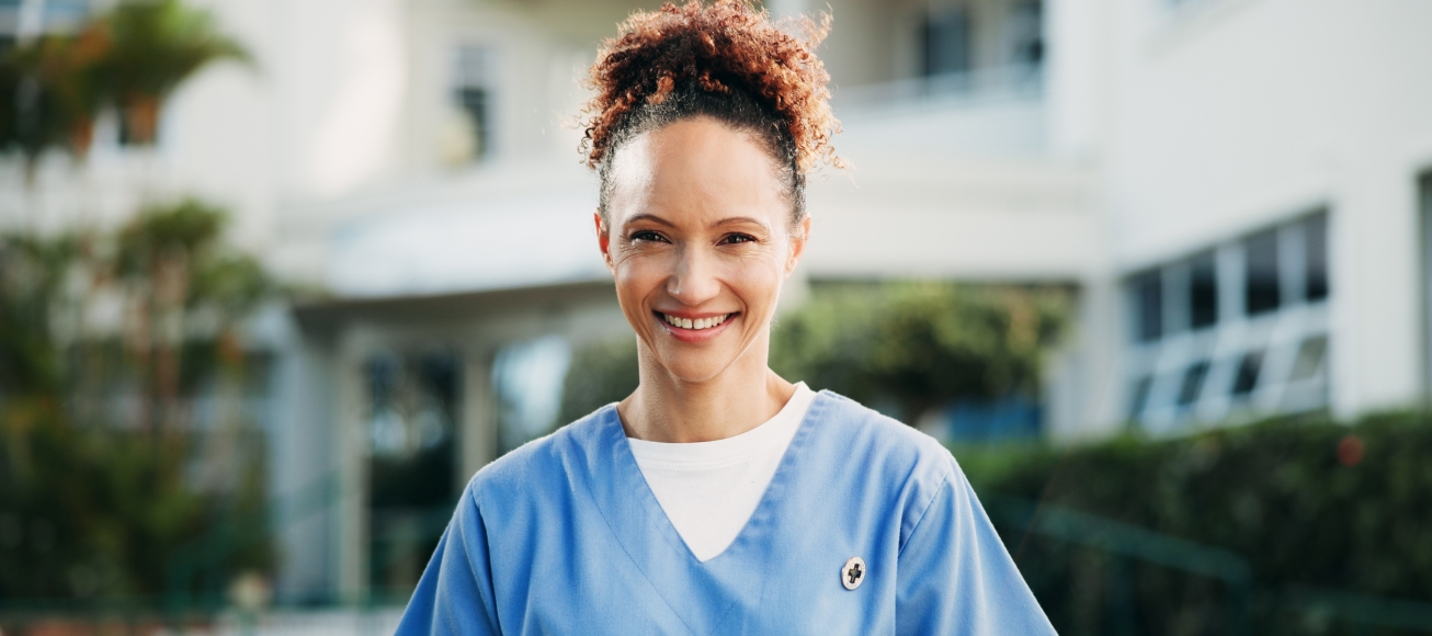 Doctora sonriente a las puertas de un hospital.