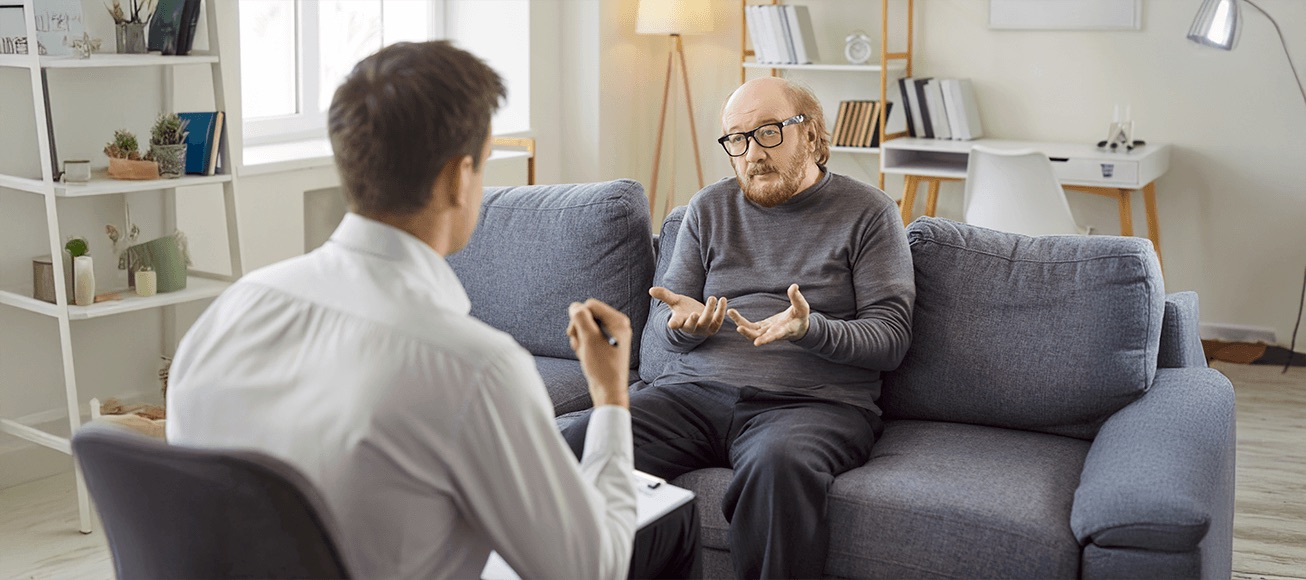 Profesional de salud mental atiende a hombre mayor, dialogando sobre bienestar tras jubilacion.