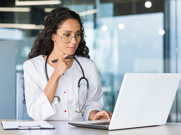 Doctora revisando documentación en su ordenador portátil.