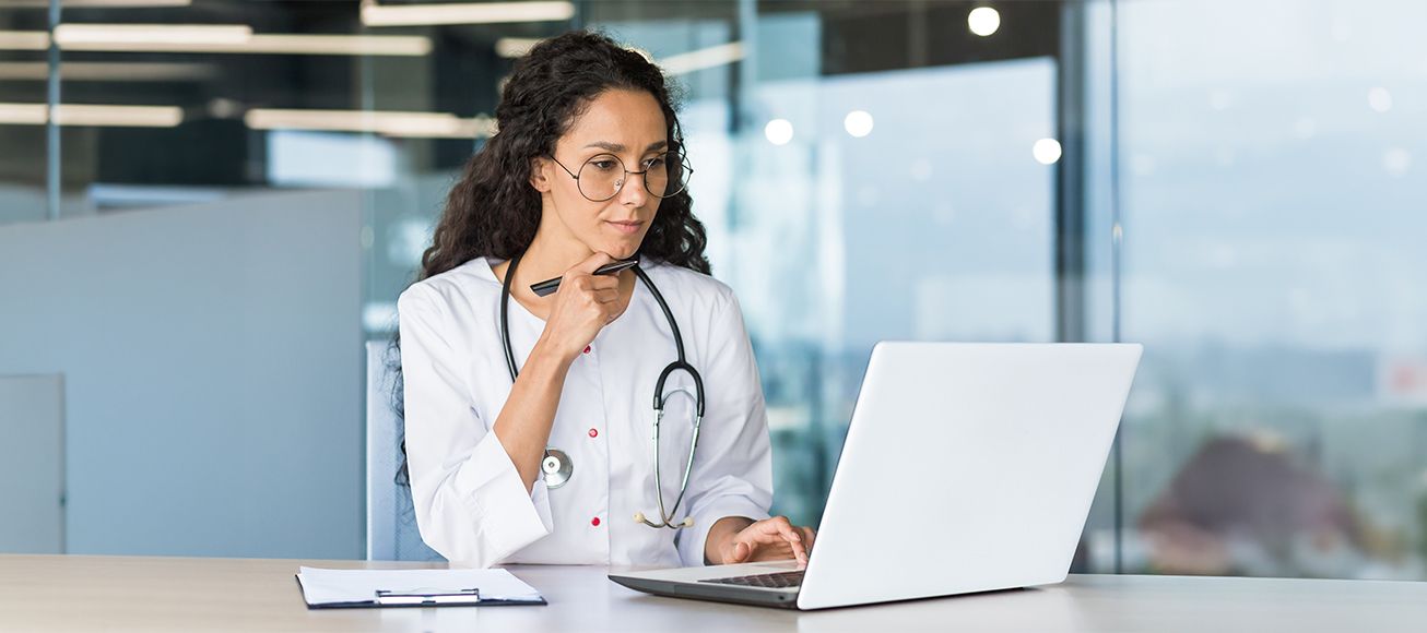 Doctora revisando documentación en su ordenador portátil.