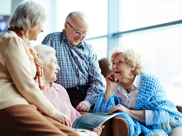 Grupo de personas mayores reunidas en un salón.