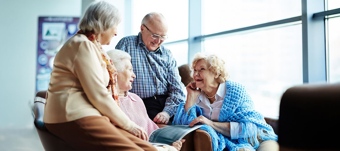 Grupo de personas mayores reunidas en un salón.