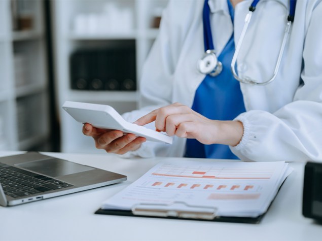 Doctora realizando el borrador de la renta con una calculadora en la mano.