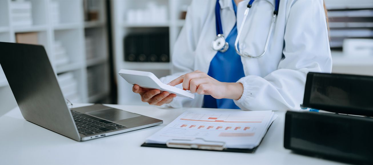 Doctora realizando el borrador de la renta con una calculadora en la mano.