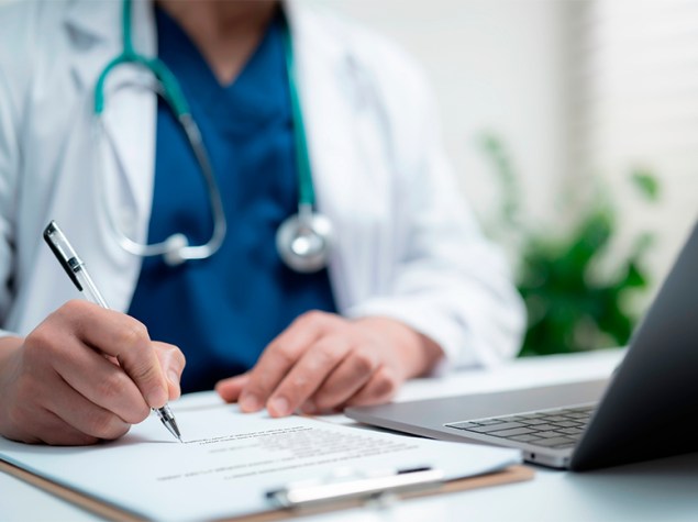 Doctor firma un contrato laboral en su mesa de trabajo.