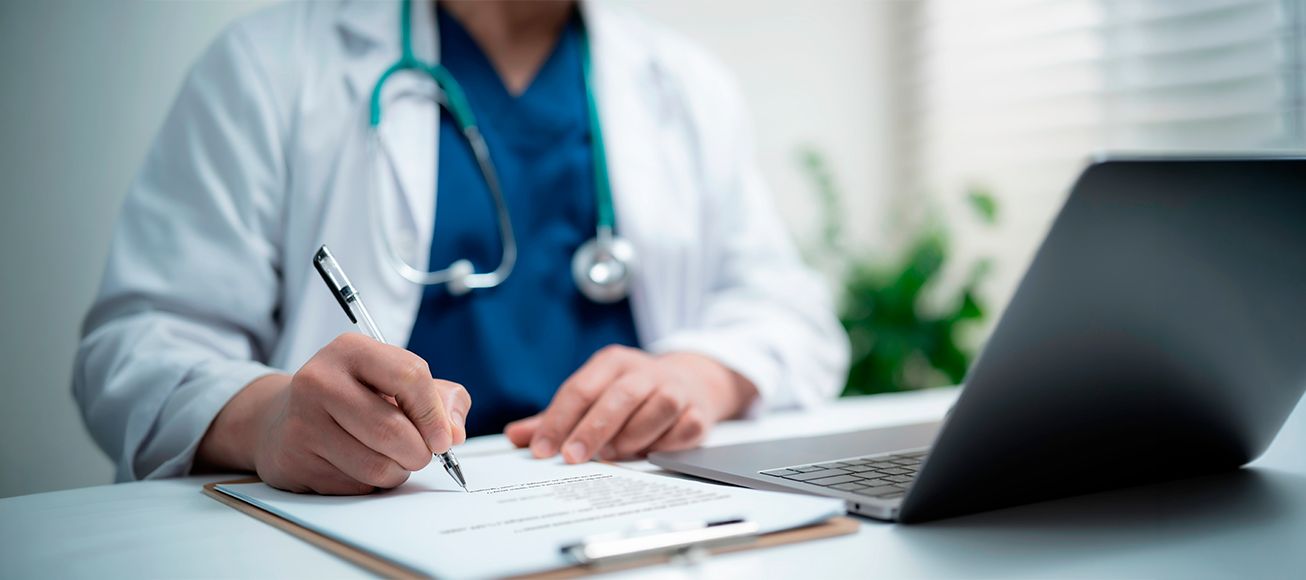 Doctor firma un contrato laboral en su mesa de trabajo.