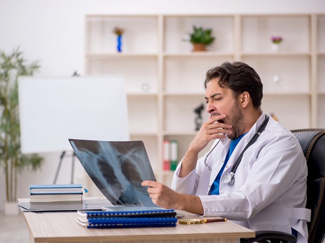 Médico analizando una radiografía mientras bozteza en una guardia.