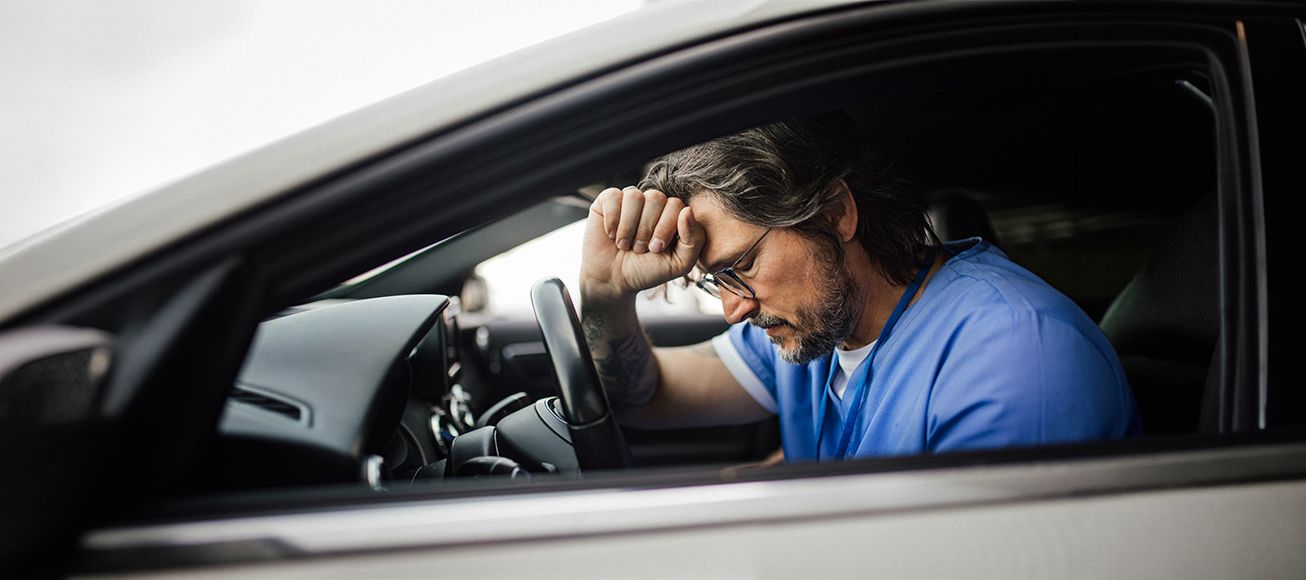 Médico en su vehículo tras un turno largo de trabajo.